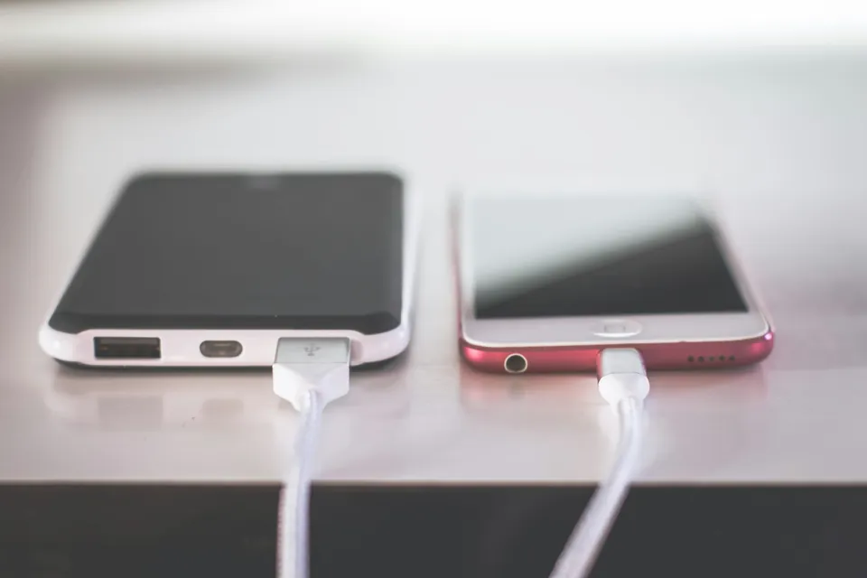 Two phones charging side by side on a white table