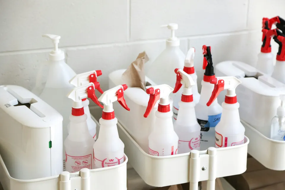 Spray bottles and refill containers lined up in a white caddy