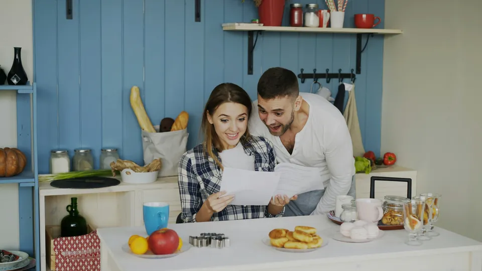 A couple reading through papers together at the kitchen counter