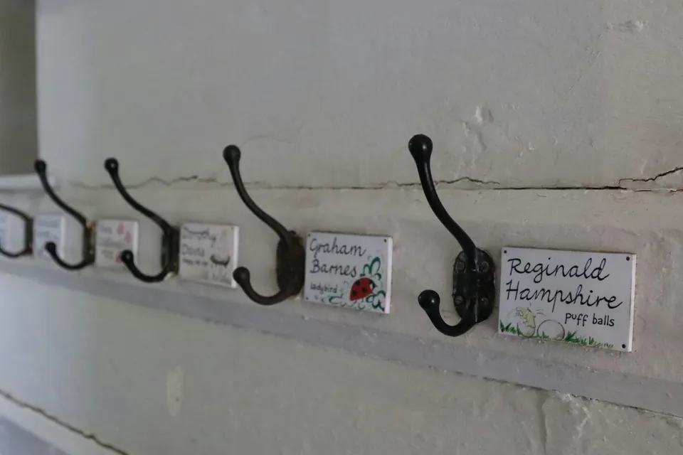 A row of coat hooks, each with a handwritten name label