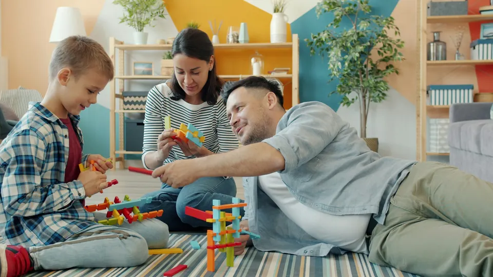 A family building with colorful toy blocks on the living room floor