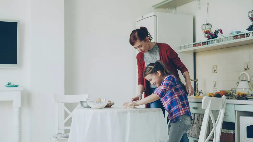 A mother and daughter cooking together in a bright kitchen