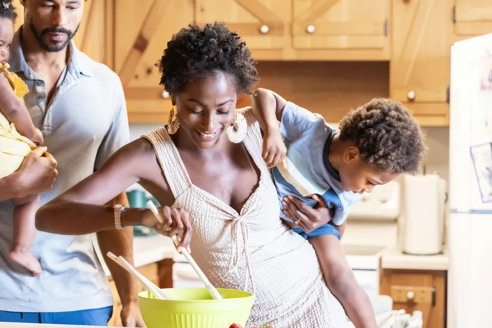 Parents cooking together in the kitchen while a child watches