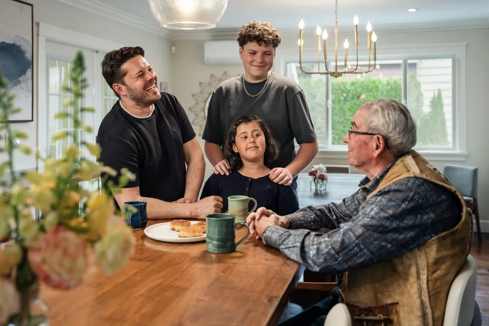 A family of four generations talking around a wooden kitchen table