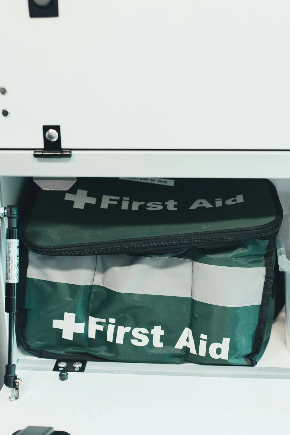 A first aid bag stored inside a white cabinet