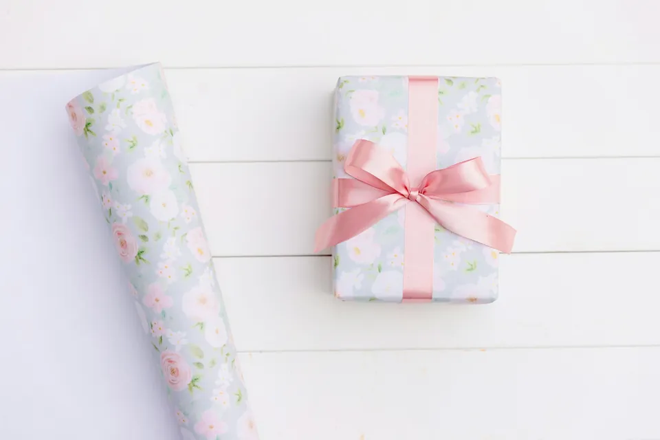 A wrapped present with a pink ribbon beside a roll of wrapping paper
