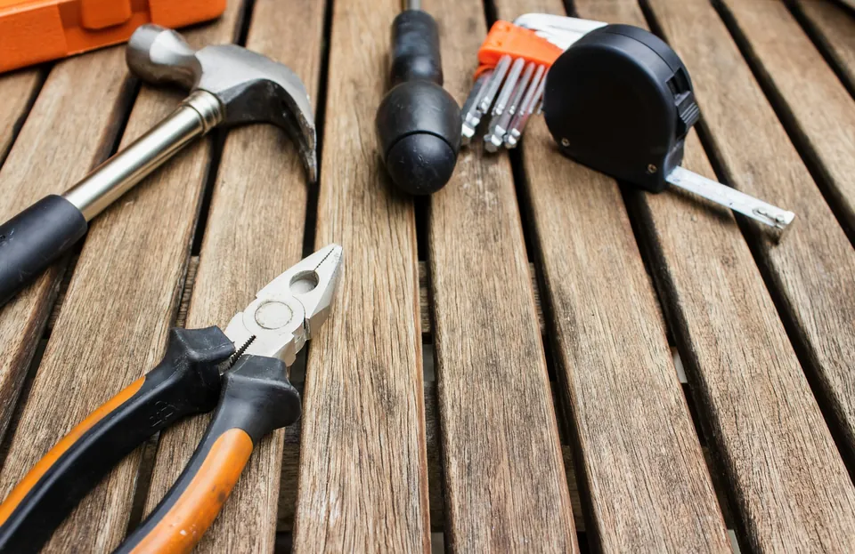 A hammer, pliers, screwdrivers and a tape measure on a wooden surface