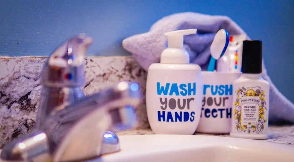 A bathroom sink with soap, toothbrushes and colorful bottles
