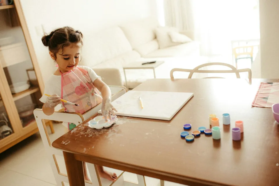 A young girl painting at the dining table