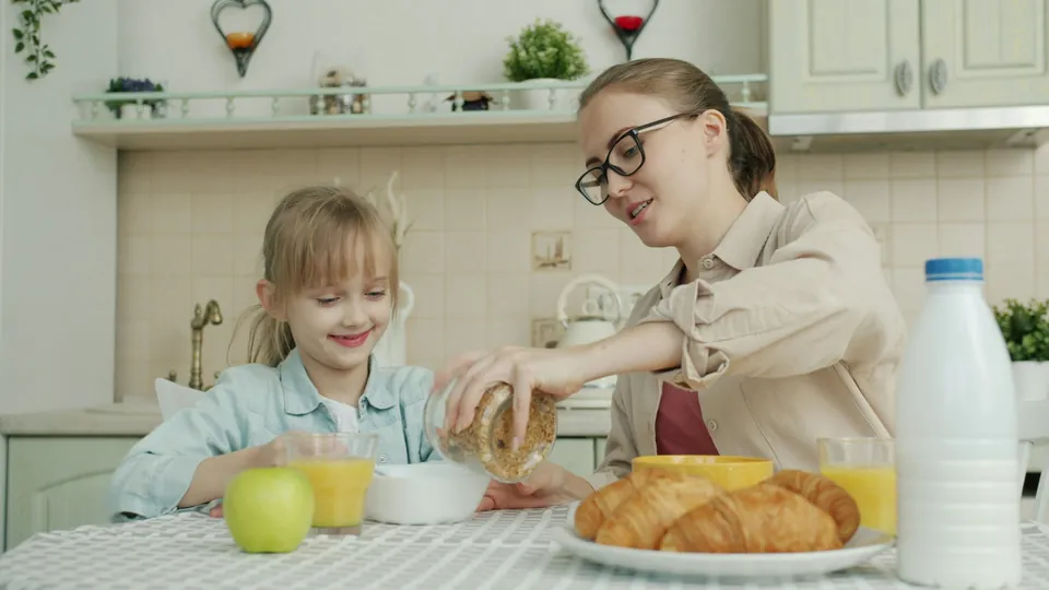 A mother and daughter eating breakfast together before school