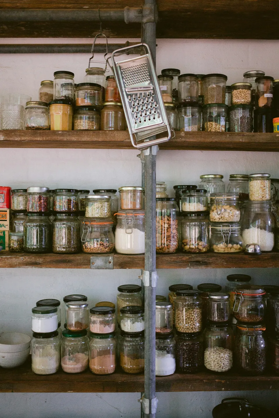 Glass jars of dry goods arranged on white shelves