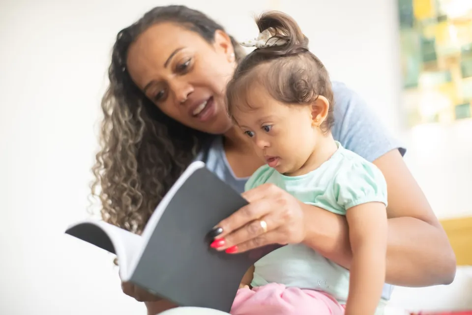 A woman reading a picture book to a toddler on her lap