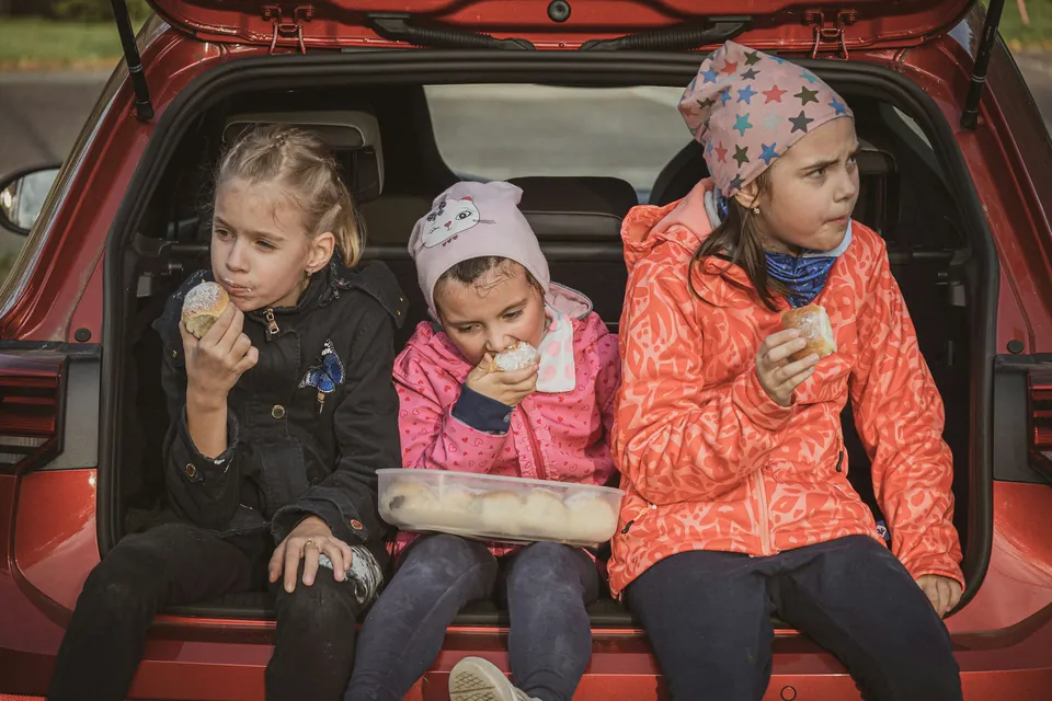 Three children sharing snacks in the back of a car